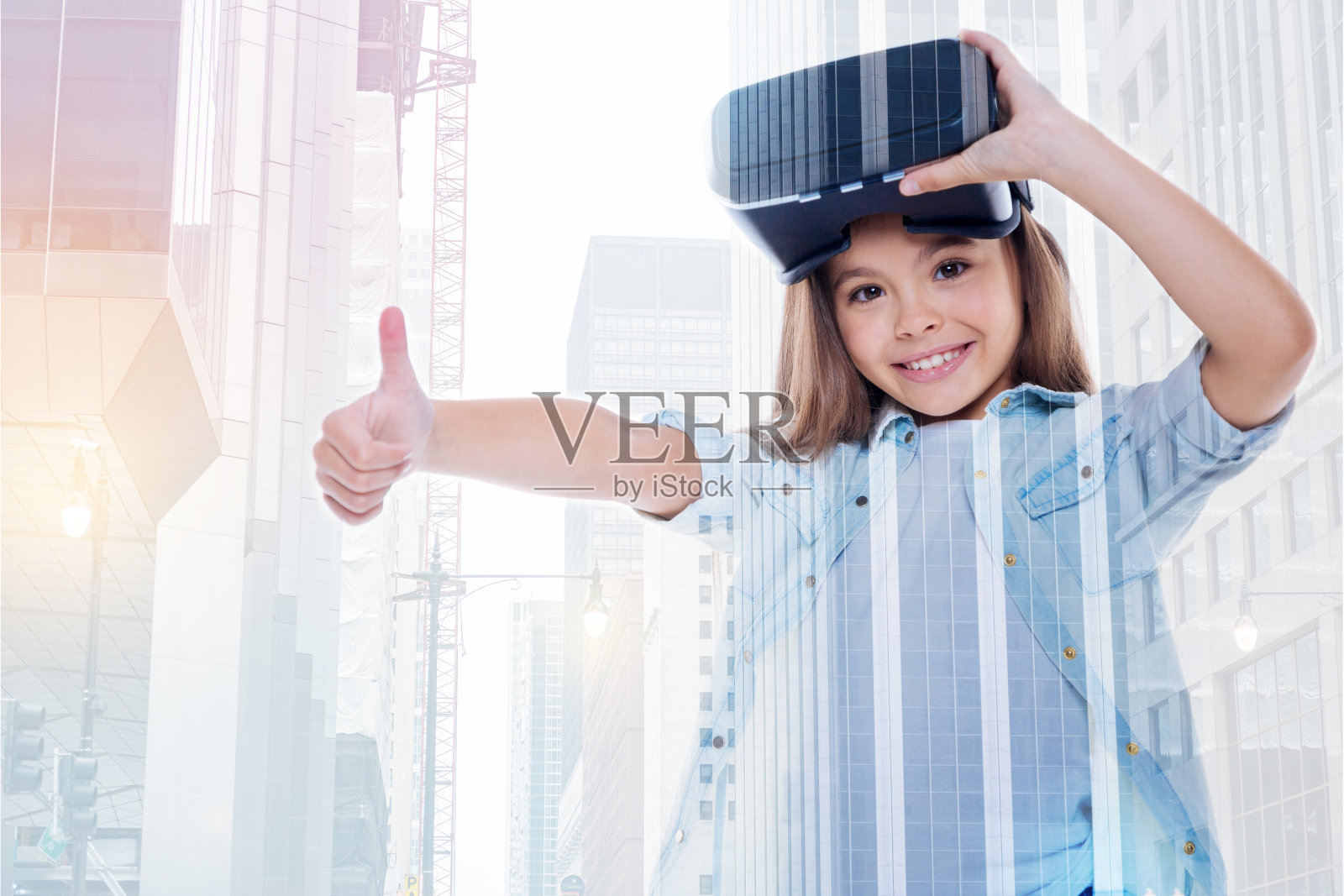 微笑的小女孩摘下VR头盔,竖起大拇指照片摄影图片