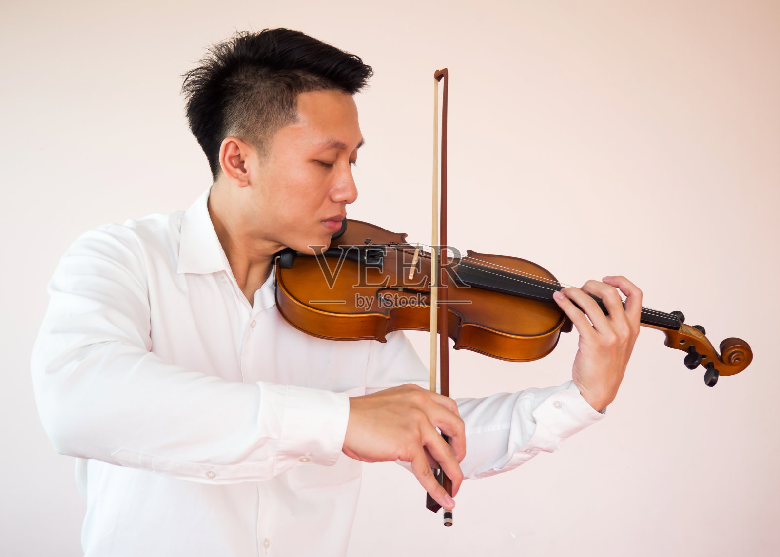 年轻的亚洲人拉小提琴。古典音乐的乐器。肖像在白色的背景。照片摄影图片