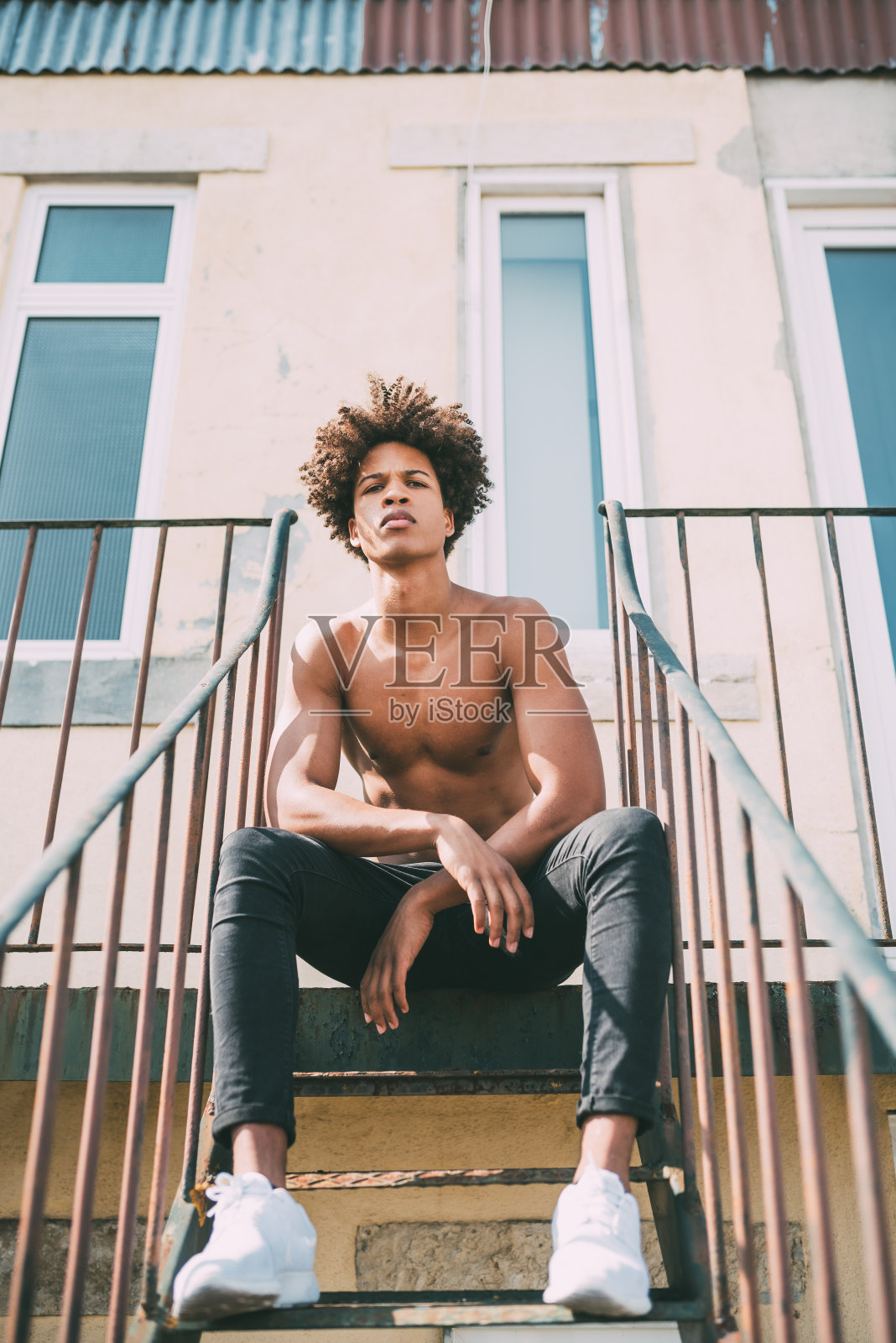 赤裸上身的黑人青年坐在楼梯上照片摄影图片