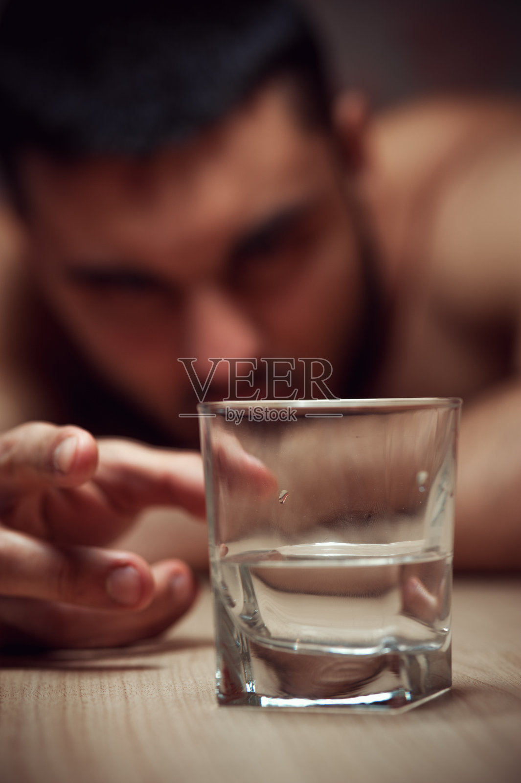 将手移向玻璃杯的醉酒年轻人照片摄影图片