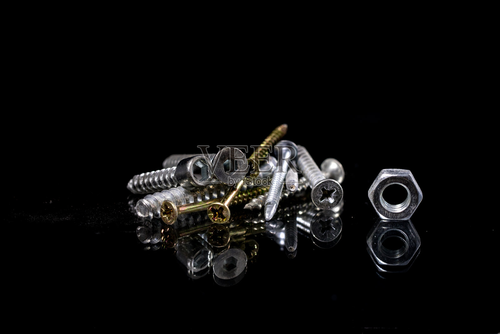 镜子里有反射的螺丝和螺丝。螺丝在玻璃镜子桌上。黑色背景。照片摄影图片