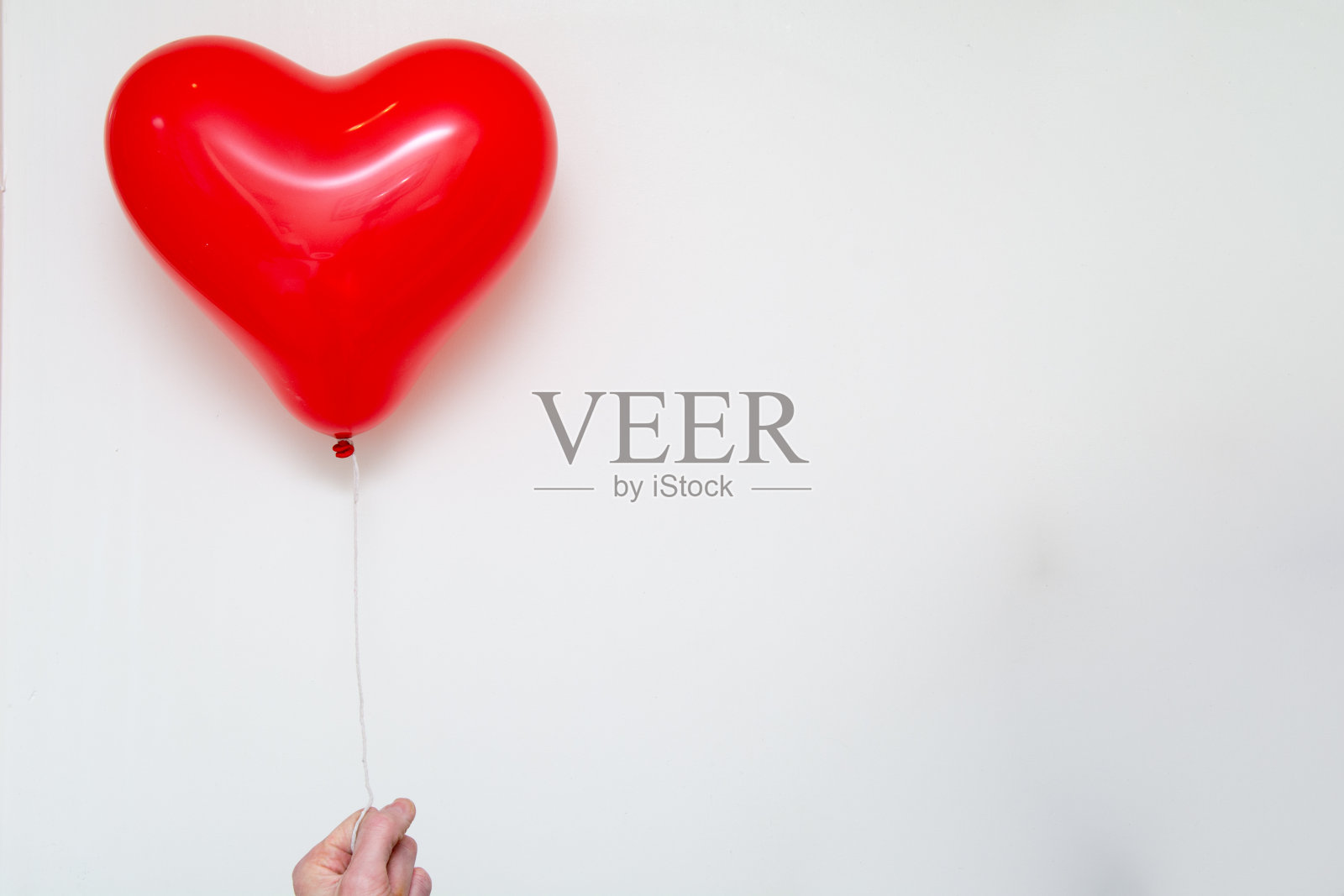 手拿一个红心气球在白色的背景照片摄影图片