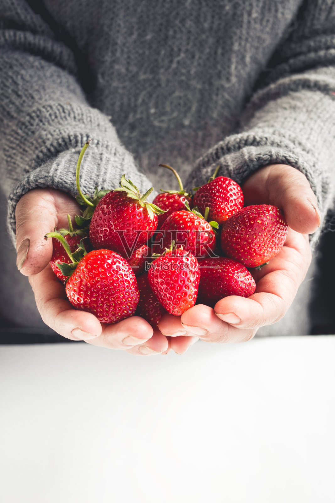 手里拿着草莓,手里拿着草莓,背景灰白色照片摄影图片