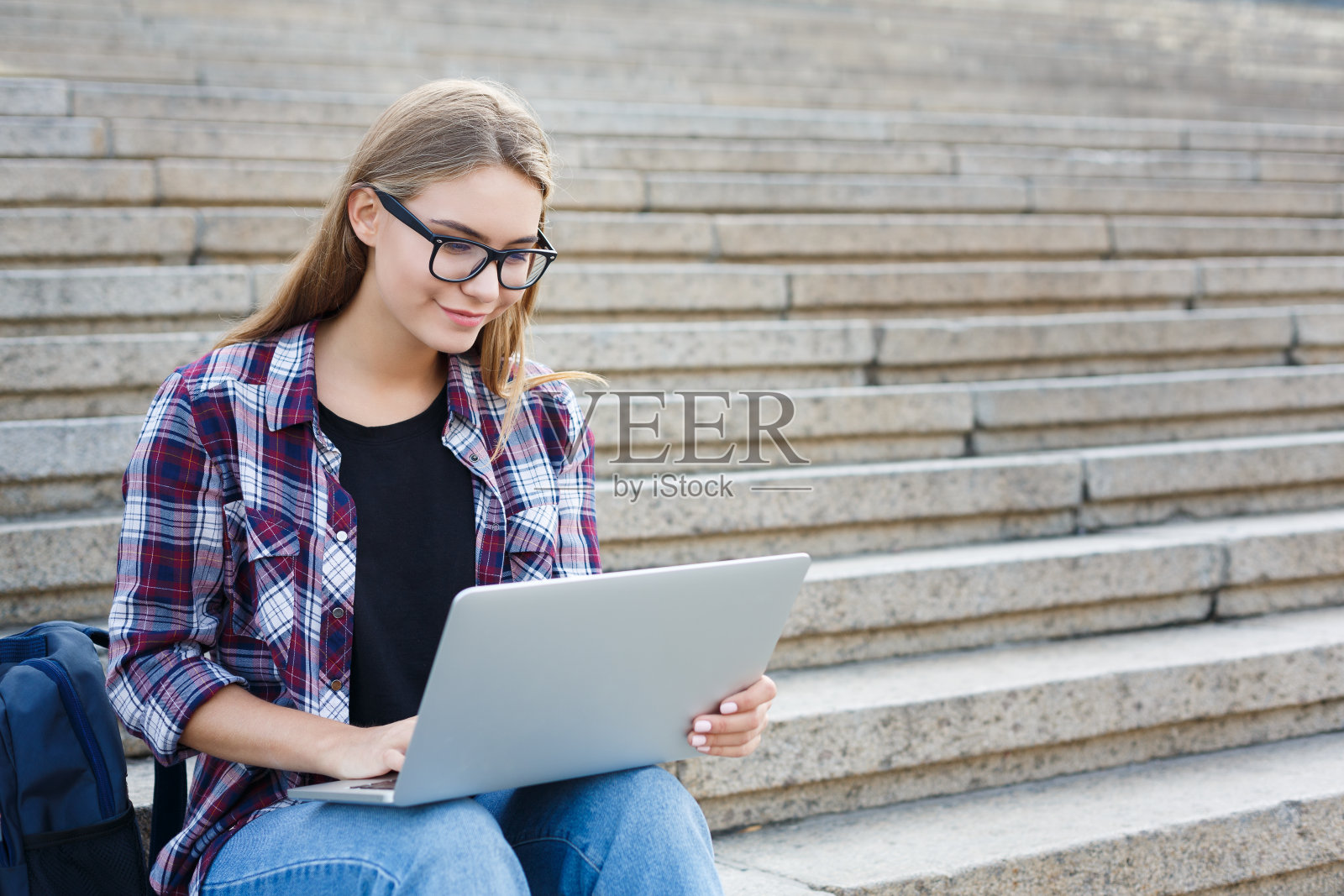 微笑的学生坐在楼梯上使用笔记本电脑照片摄影图片