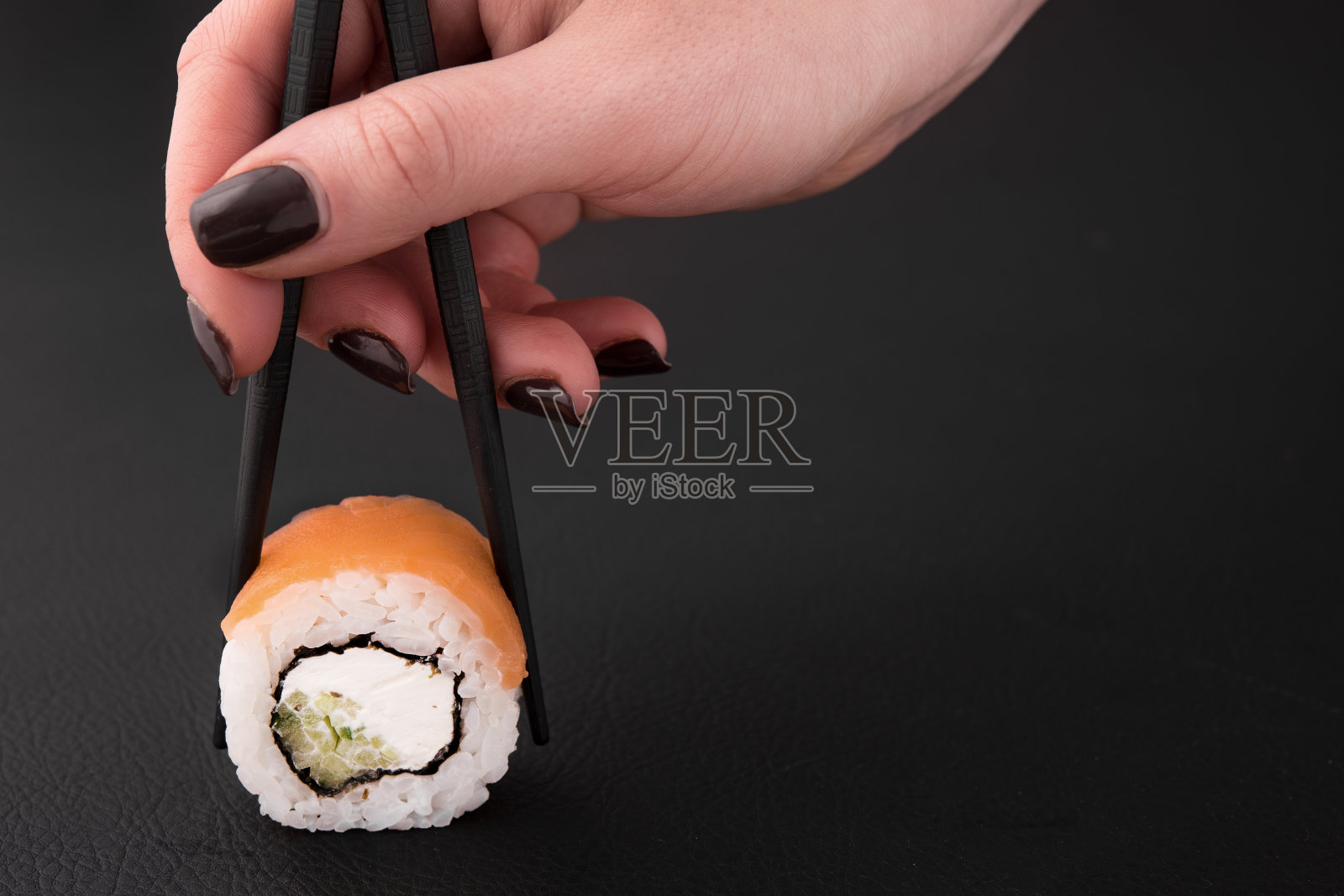 女人手里拿着一个寿司卷照片摄影图片