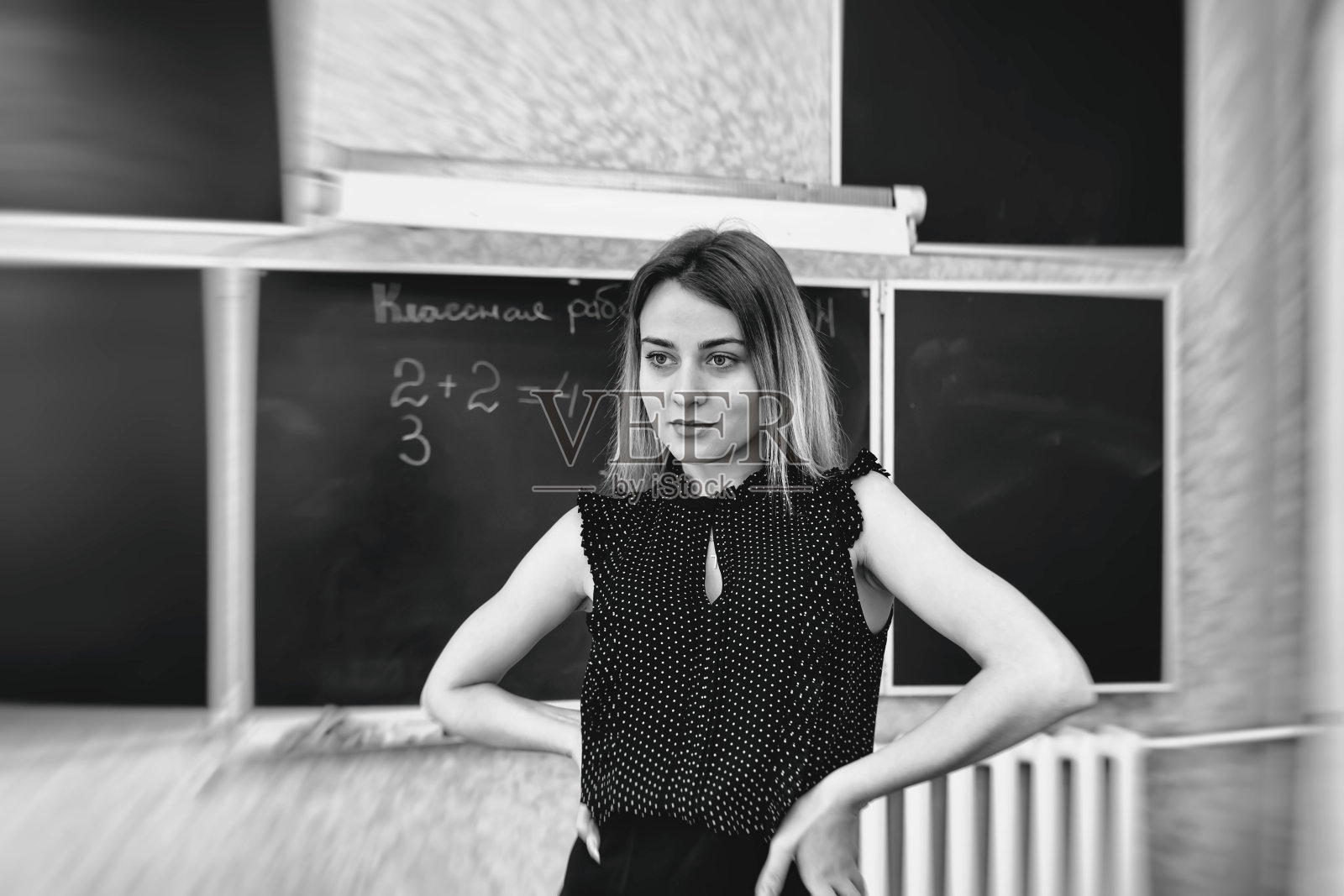 严厉的金发年轻老师站着,双手叉腰照片摄影图片