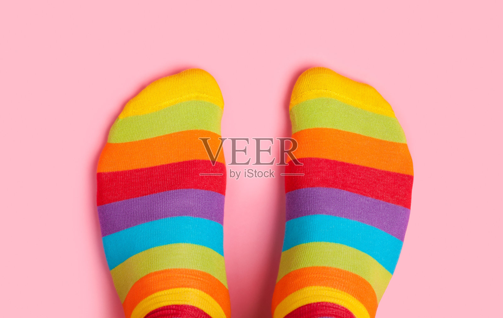 脚在彩虹色袜子粉红色的背景照片摄影图片