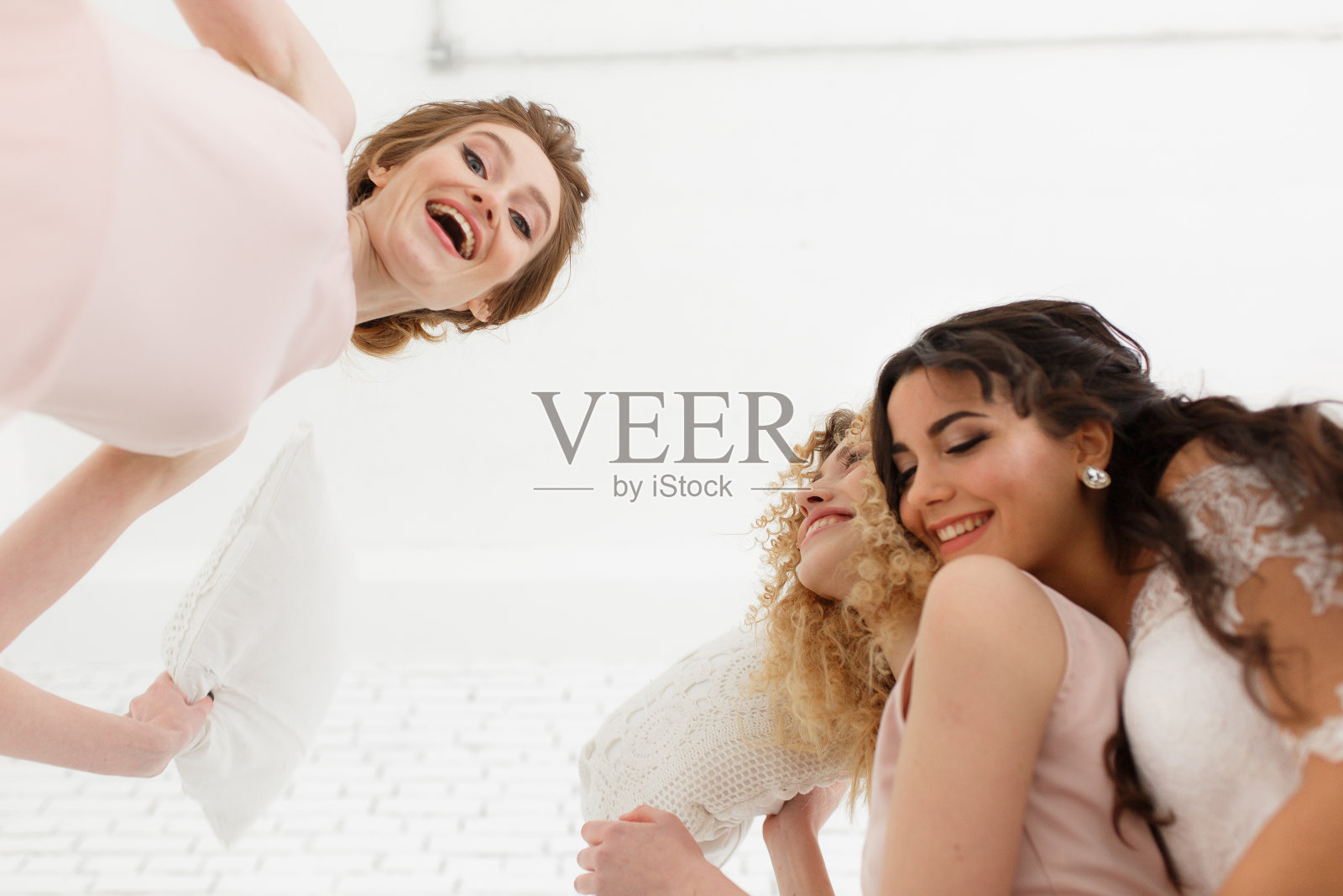 感觉如此快乐。从下面看,美丽的年轻新娘和两个伴娘在试衣间自拍时做鬼脸照片摄影图片