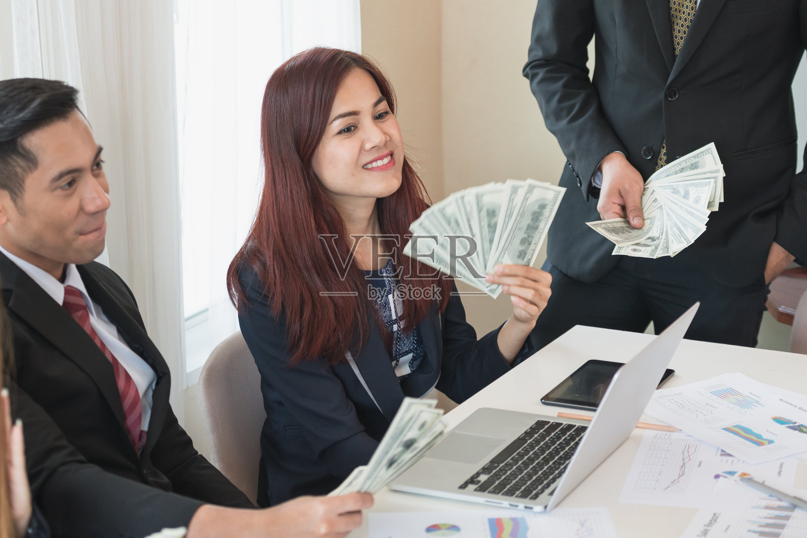 亚洲商界男女团体,事业有成。有很多钱。办公桌上放着笔记本电脑和文件。企业成功的概念照片摄影图片