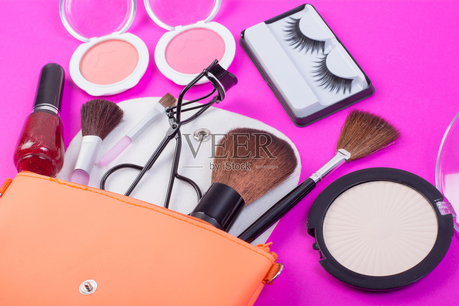 俯视图的化妆包,化妆品溢出到粉红色的背景。照片摄影图片