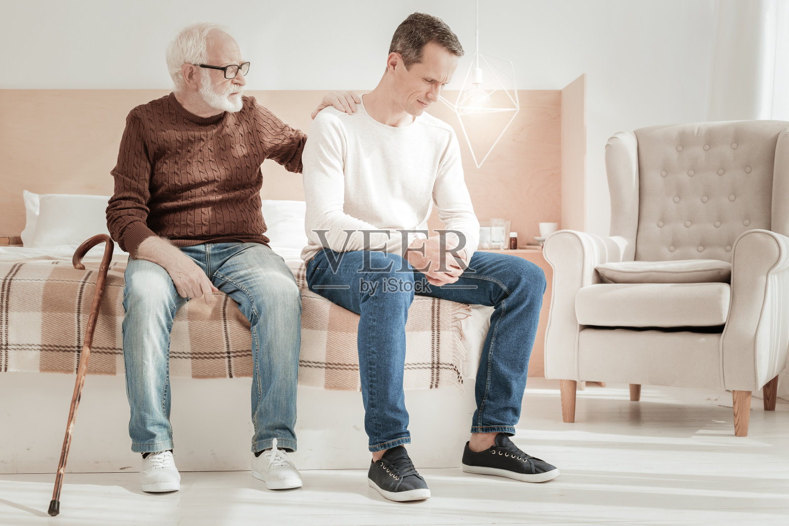 不快乐的悲伤的人坐着,向下看。照片摄影图片