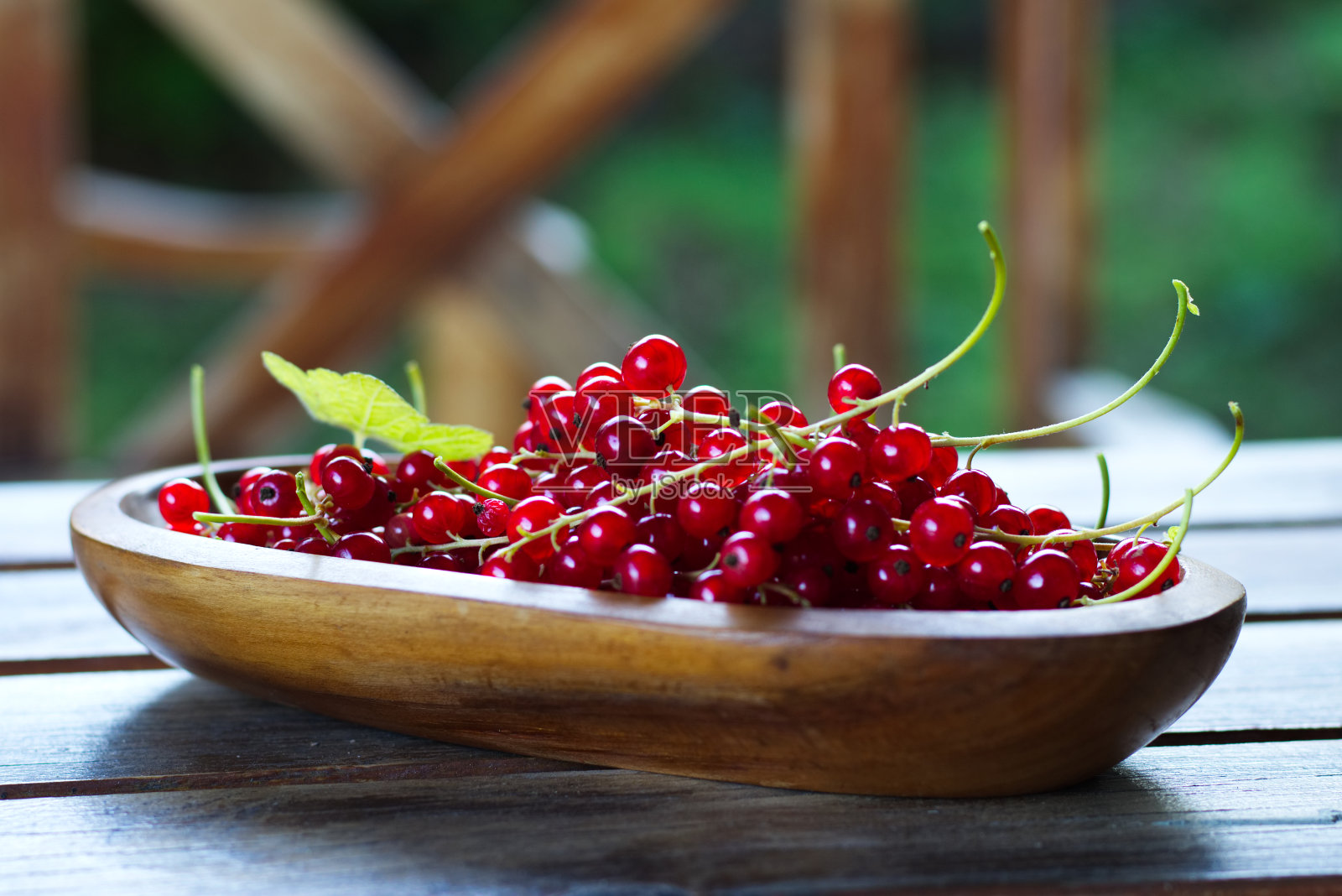 收获成熟的红醋栗放在桌子上的木碗里照片摄影图片