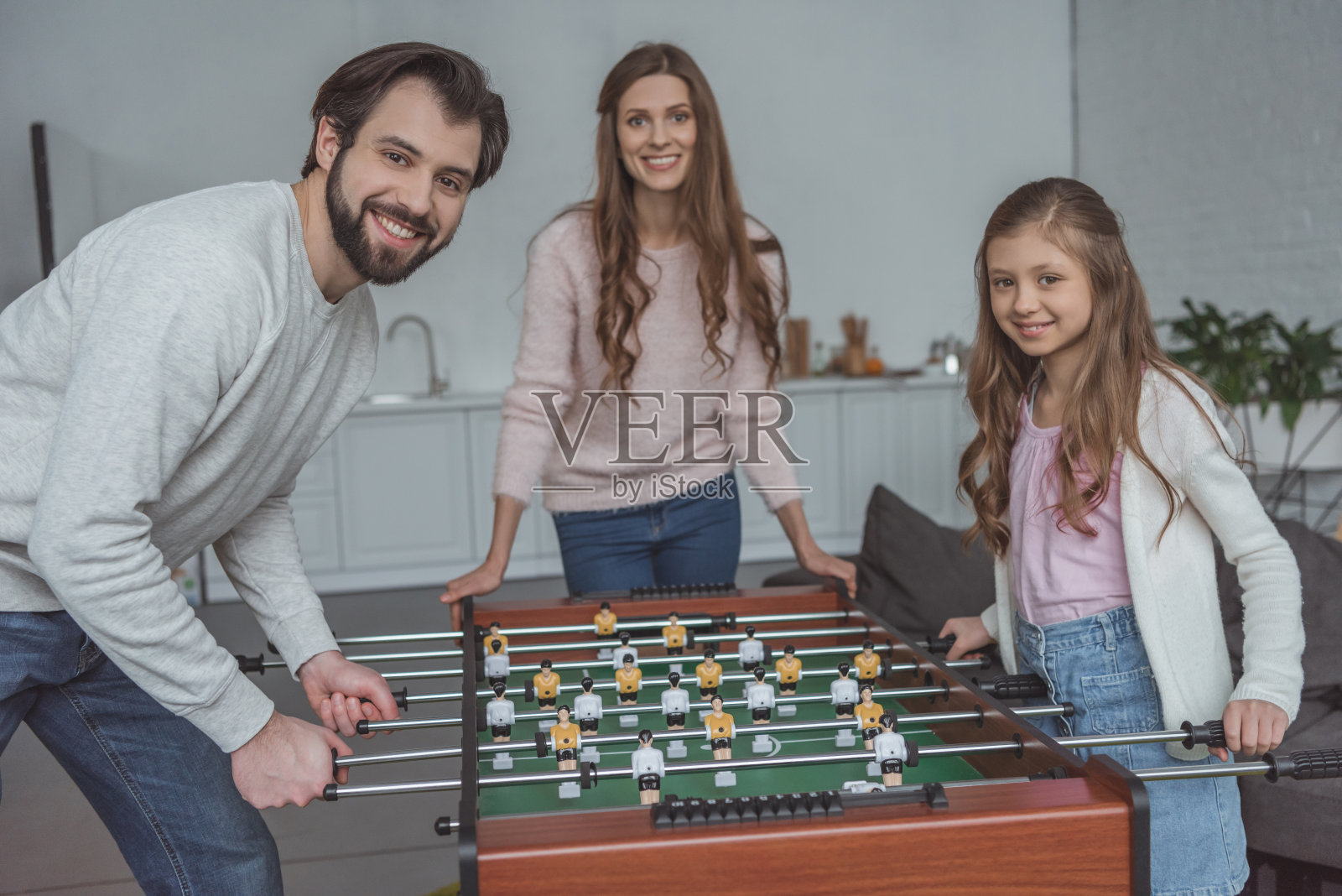 父亲和女儿在家里玩桌上足球,看着摄像机照片摄影图片