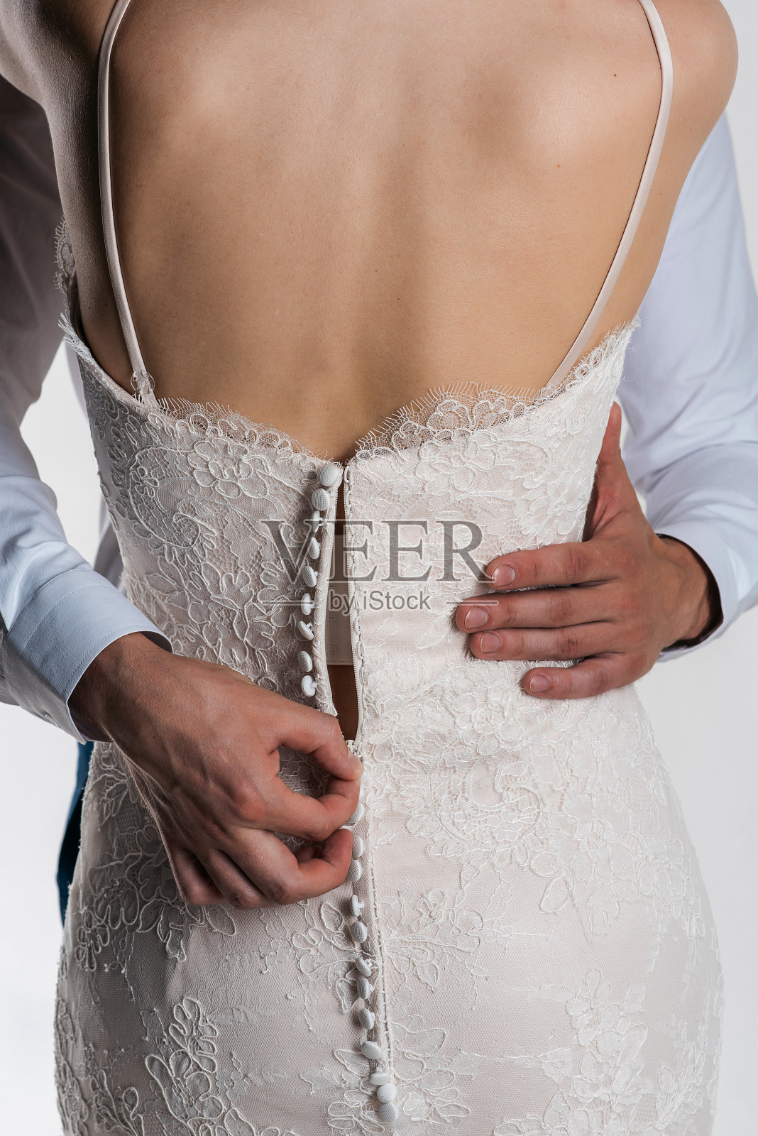 新郎给新娘脱衣服。从后面看。结婚的那一天照片摄影图片