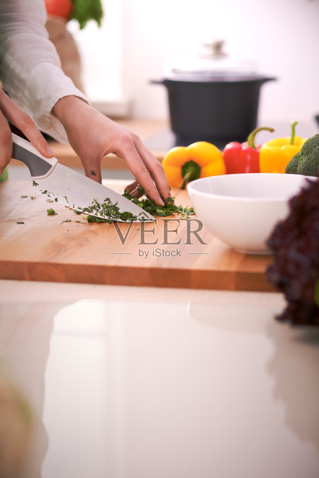 人的双手烹饪蔬菜沙拉在厨房的玻璃桌上反射。健康饮食和素食的概念照片摄影图片