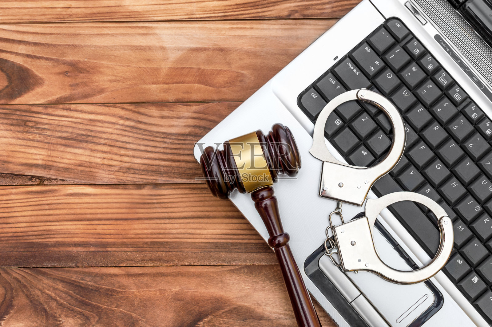 桌上放着手提电脑,还有小木槌和手铐。网络犯罪的概念。前视图。为文本复制空间。照片摄影图片