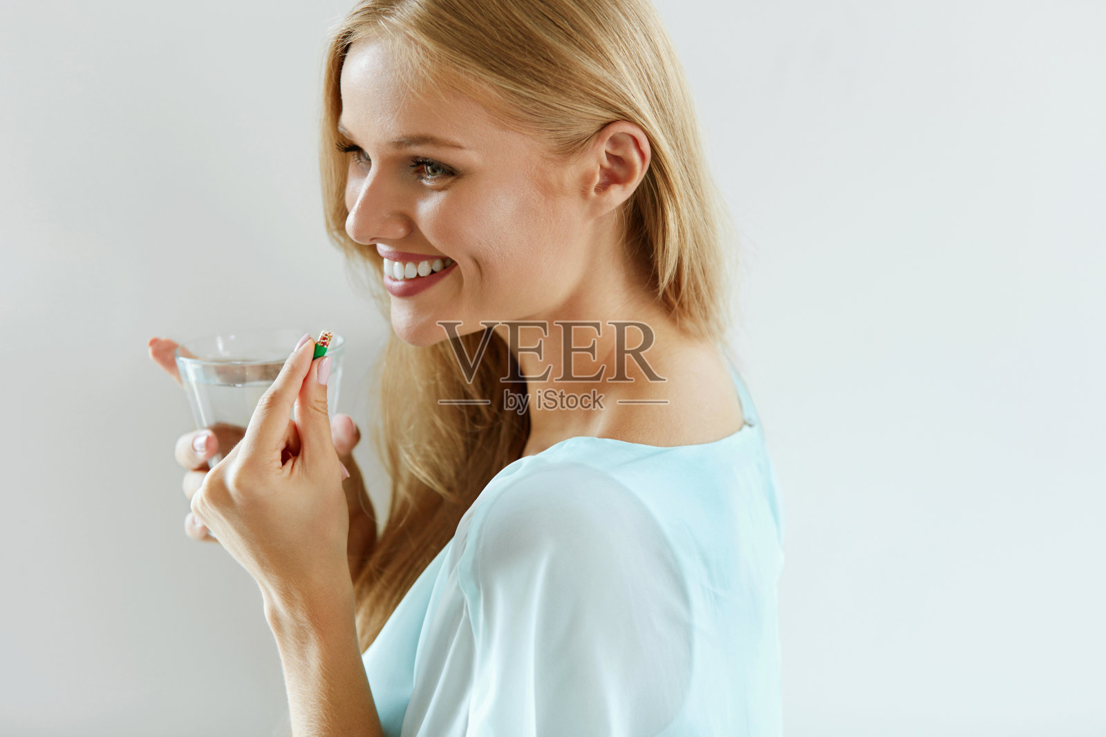 美丽微笑的女人服用维他命药丸。膳食补充剂照片摄影图片