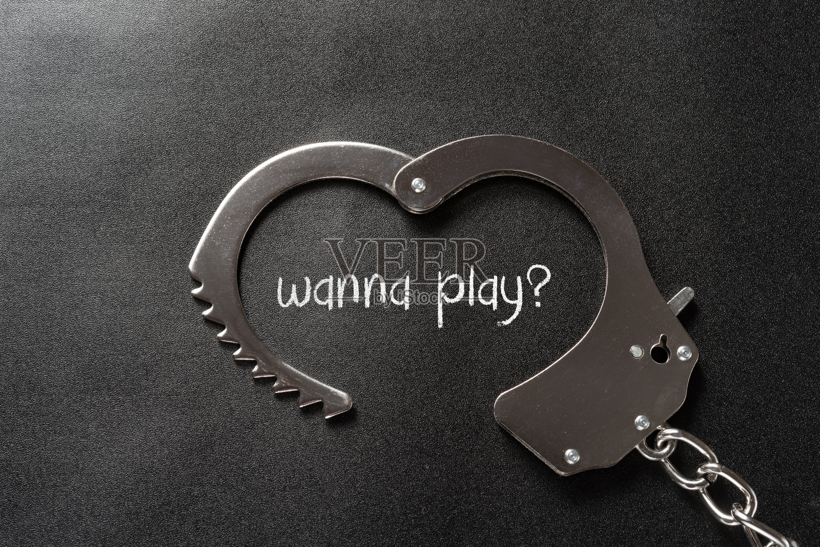 手铐的形状像一颗心在黑色和写着想玩照片摄影图片