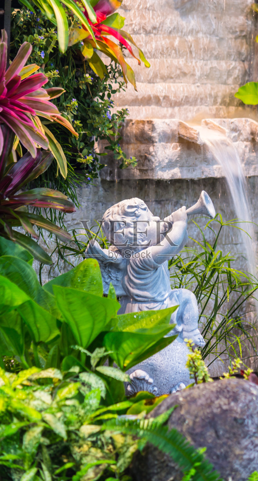 在舒适的花园里的丘比特雕像。照片摄影图片