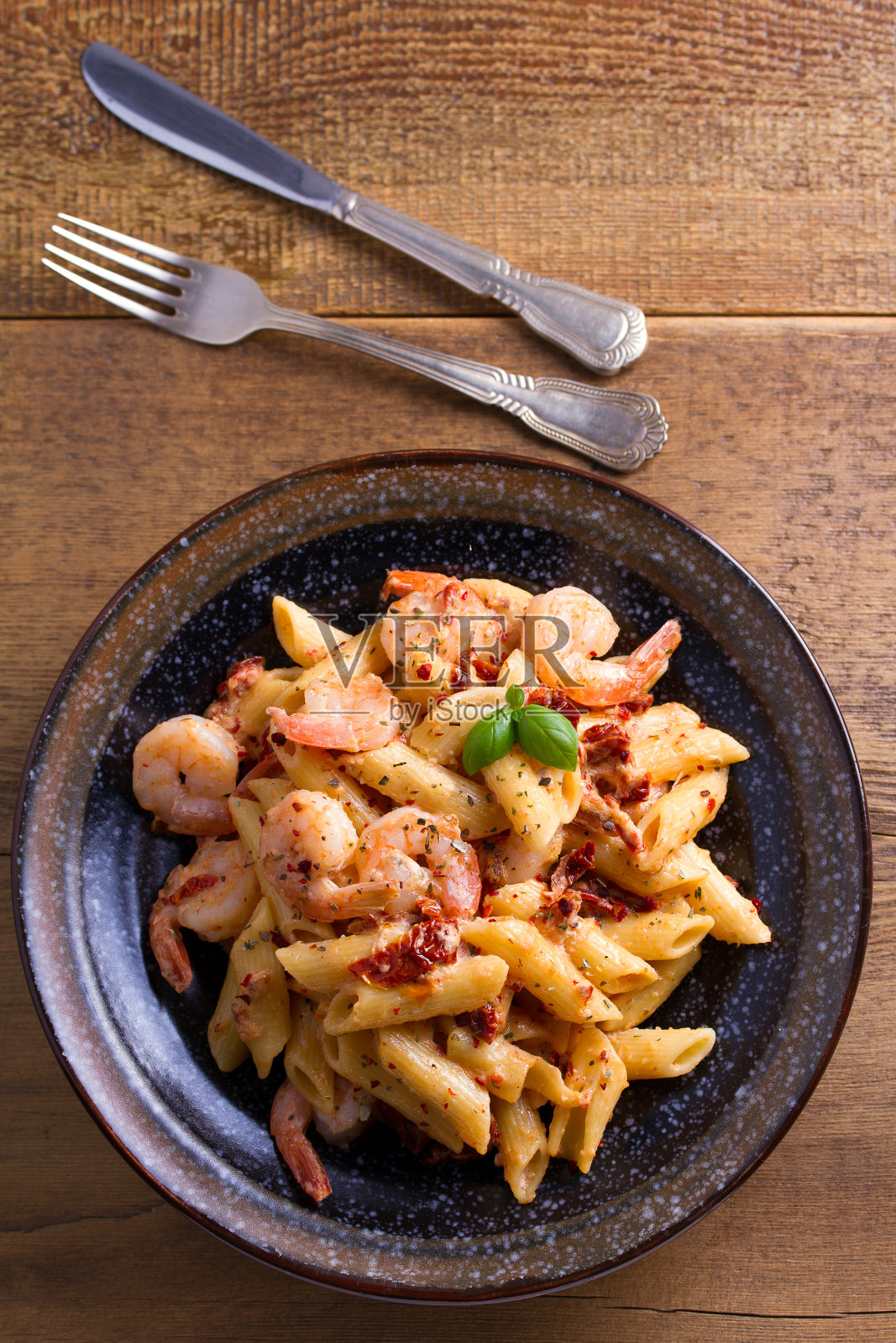鲜虾意大利面,晒干的西红柿和罗勒在奶油马苏里拉酱照片摄影图片