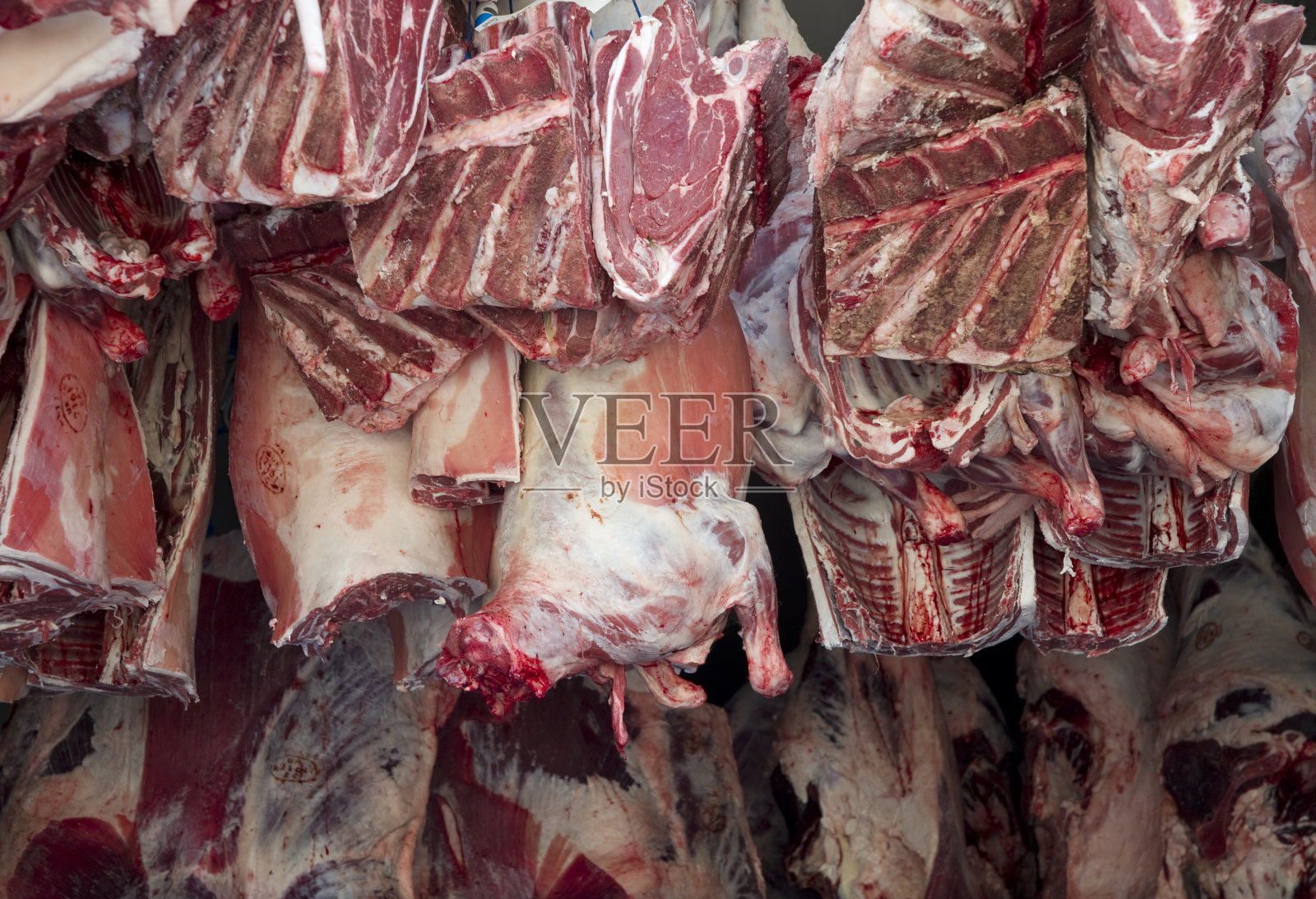 肉被送到挂在钩子上的屠夫手中照片摄影图片