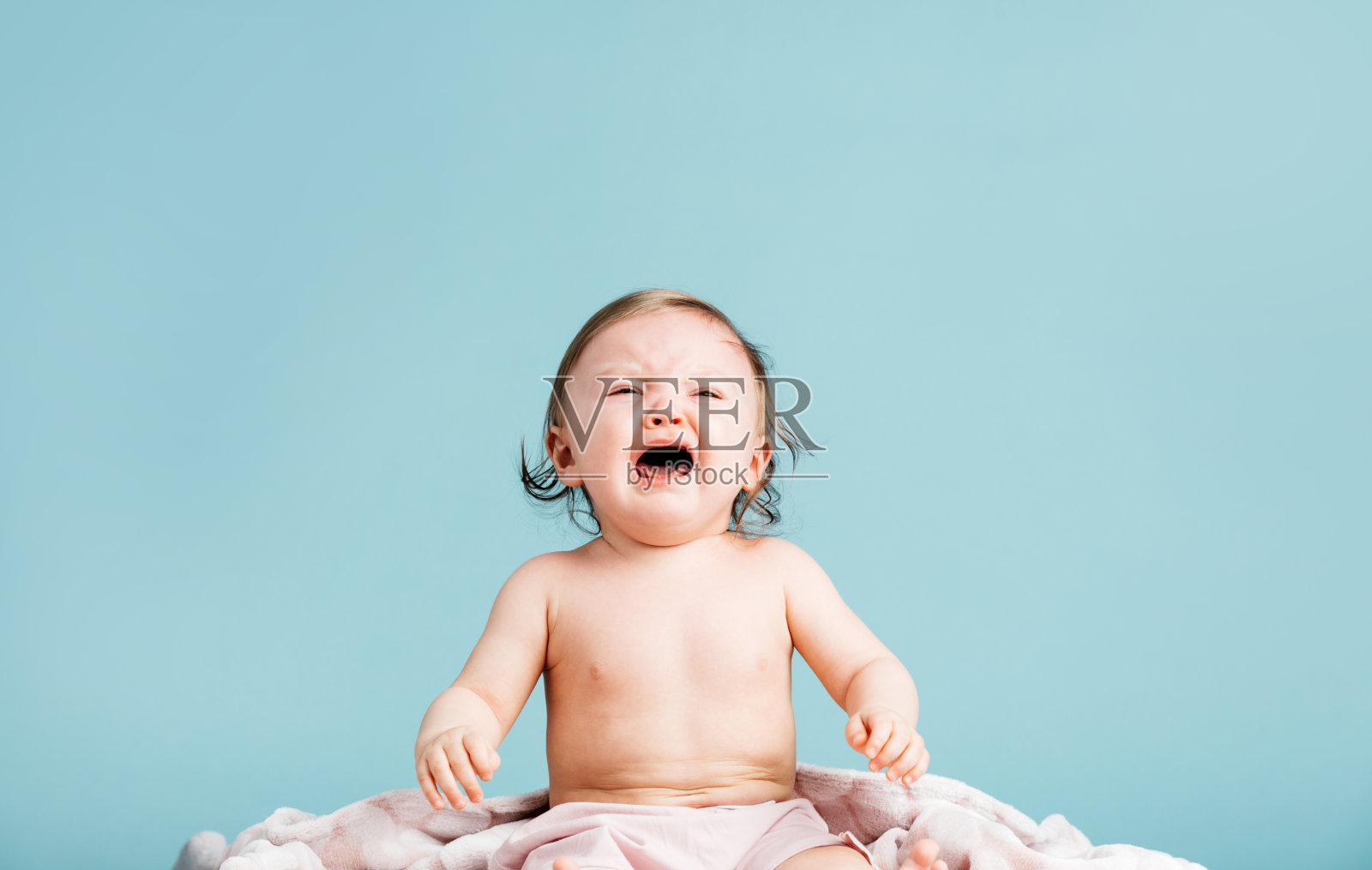 坐在毯子上哭泣的小女孩照片摄影图片