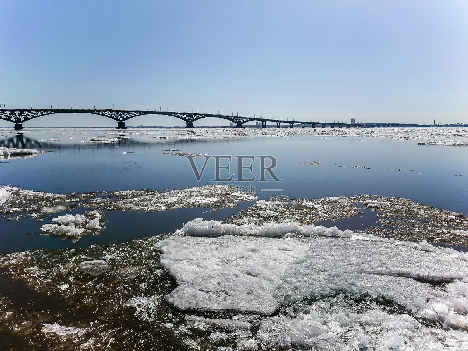 俄国萨拉托夫和恩格斯之间伏尔加河上的公路桥。春天河上有冰漂流。萨拉托夫市的河堤。四月的晴天照片摄影图片