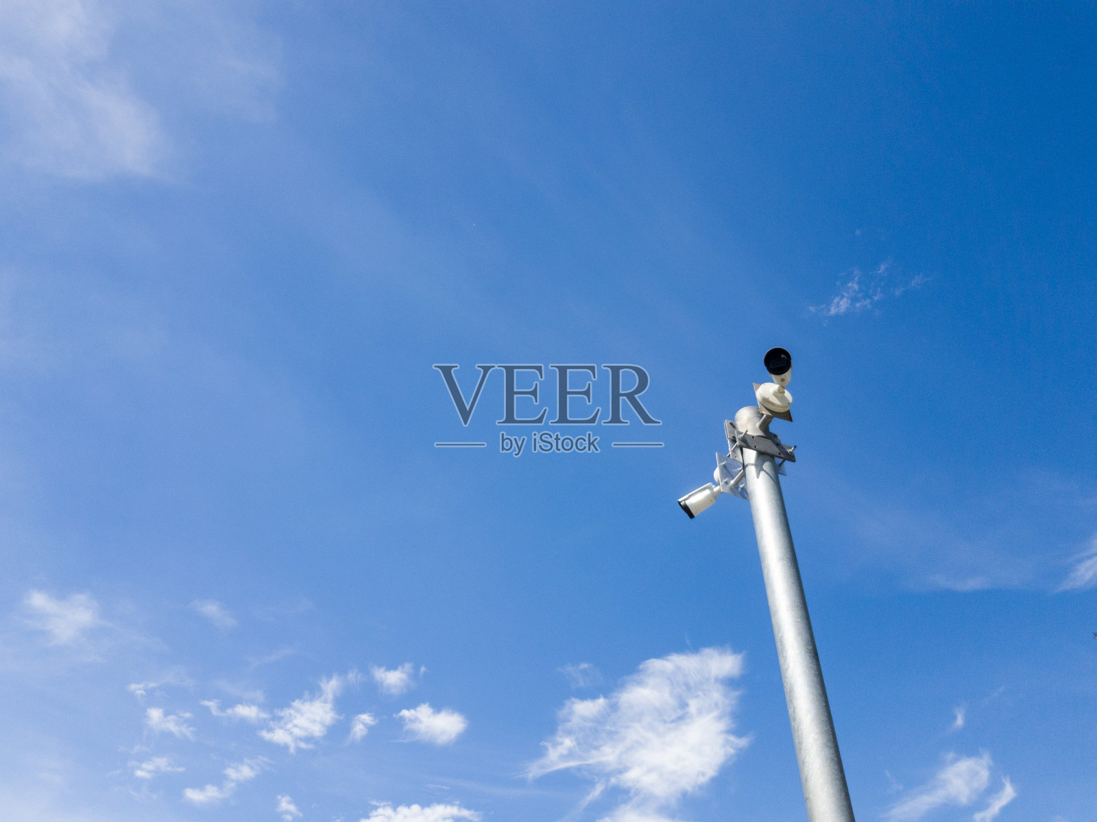 白色安全摄像头安装在高杆子上,映衬着蓝天白云。闭路电视或安全概念。照片摄影图片