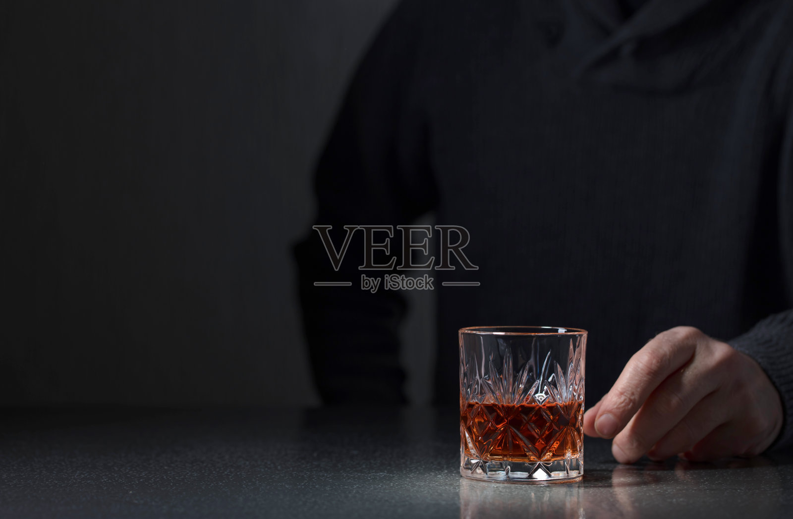 一个男人伸手去拿一杯酒。照片摄影图片