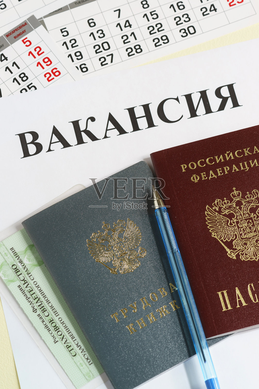工作日历和俄文文件:工作簿,护照和保险证明放在桌上。《俄国空缺》中的题词照片摄影图片