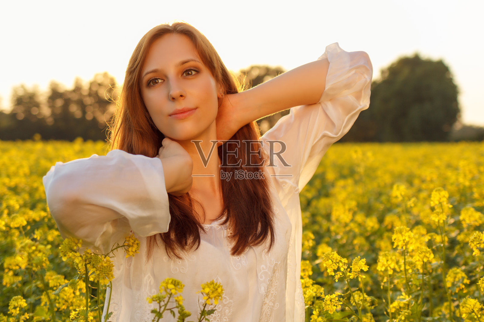 年轻的白人妇女在油菜花的领域摆姿势照片摄影图片