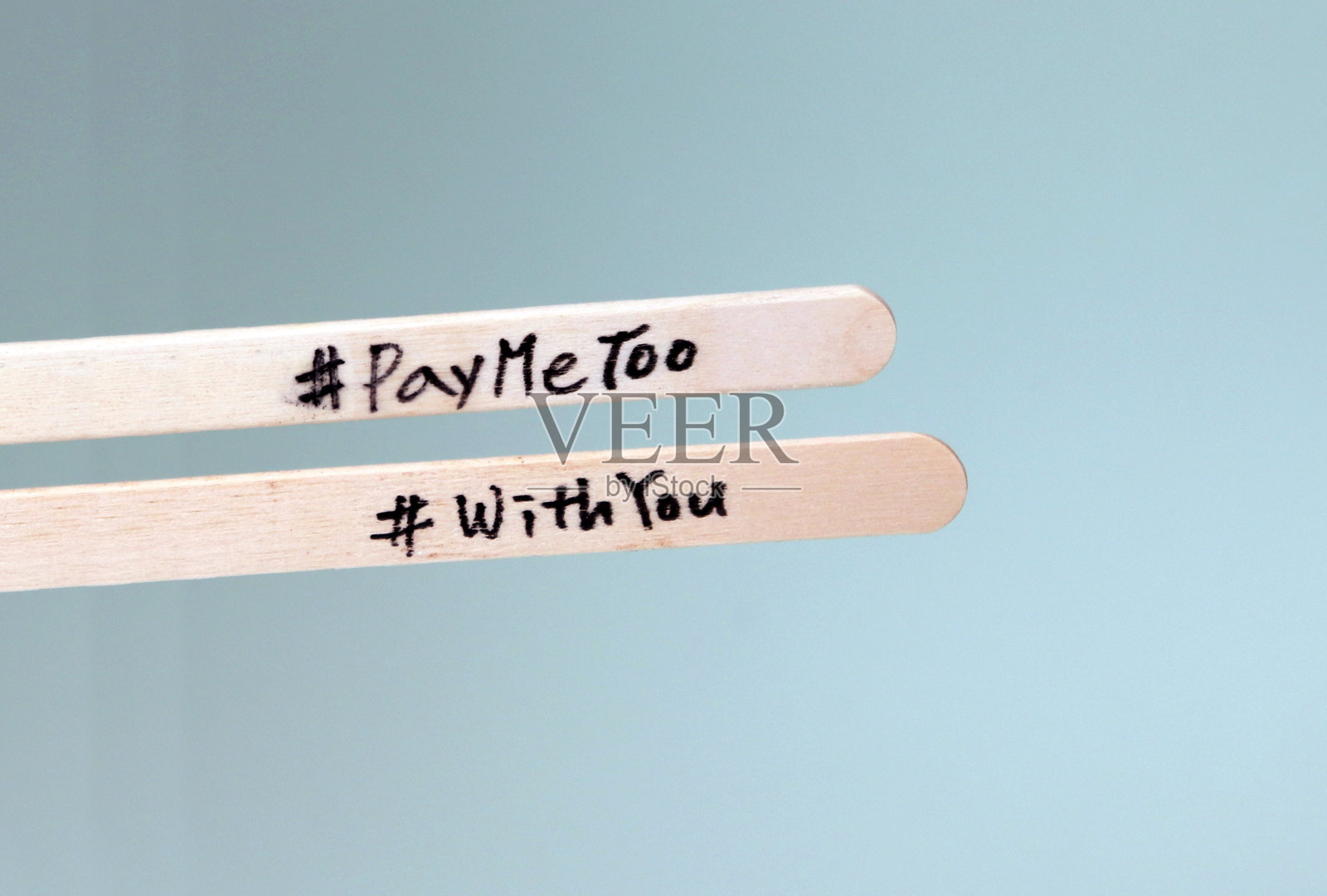 #PayMeToo是一项旨在缩小男女工资差距的新运动。一根写着#PayMeToo的木棒和一根写着#WithYou的木棒。照片摄影图片