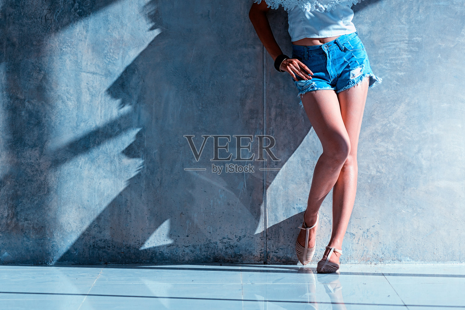 性感长腿女人牛仔裤短裤时尚站到墙照片摄影图片