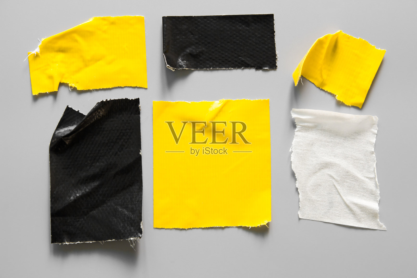 一套黄色和黑色磁带在灰色背景。撕平不同大小的黑色胶带,粘片。照片摄影图片