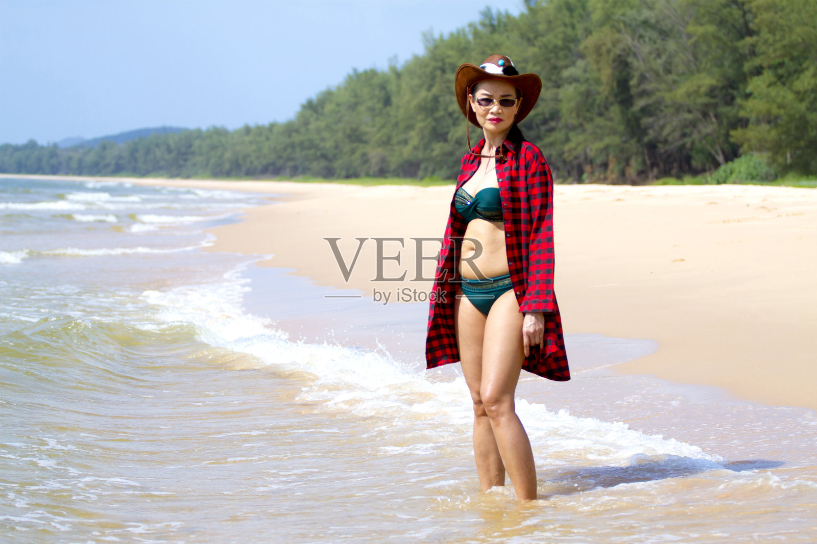 在海滩上穿着比基尼和帽子的女人照片摄影图片