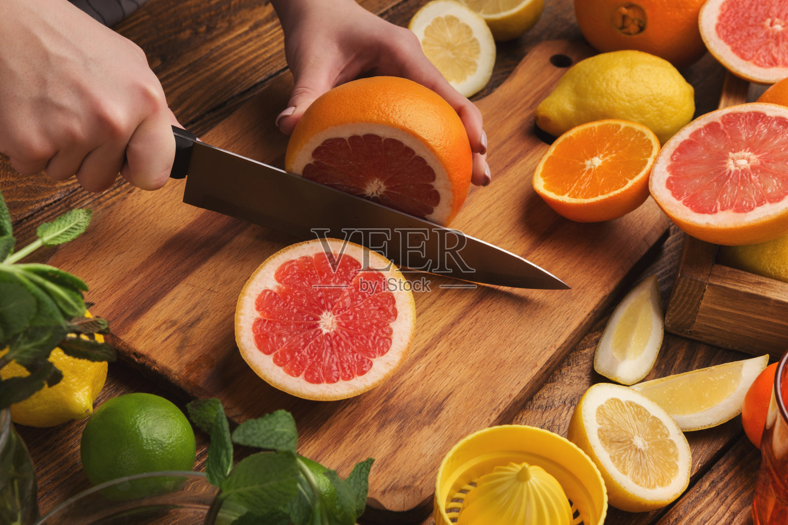 女性的手在木板上切割柑橘类水果照片摄影图片