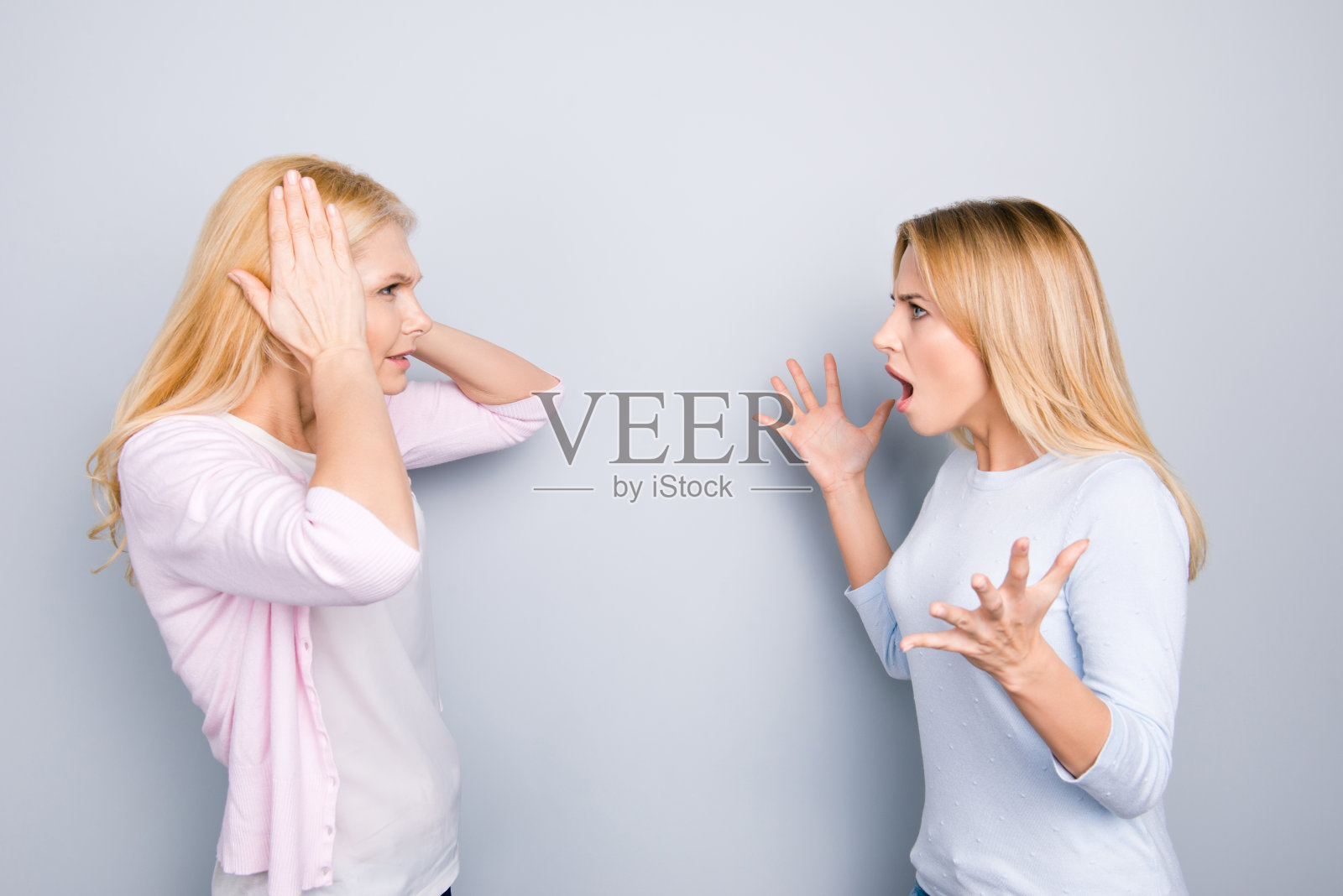 紧张、易怒、沮丧的女儿对她抑郁的妈妈大喊大叫,闭上耳朵,用手掌捂着耳朵,不理会争吵,用双手孤立在灰色背景上做手势照片摄影图片