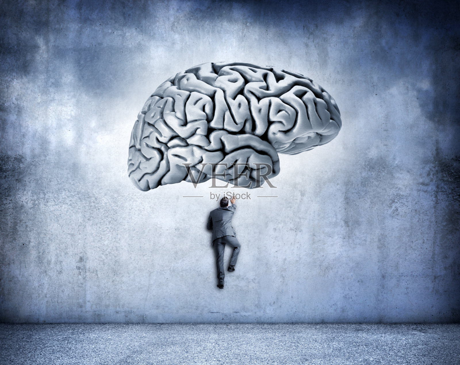 男人攀爬墙壁,上方是巨大的人脑照片摄影图片
