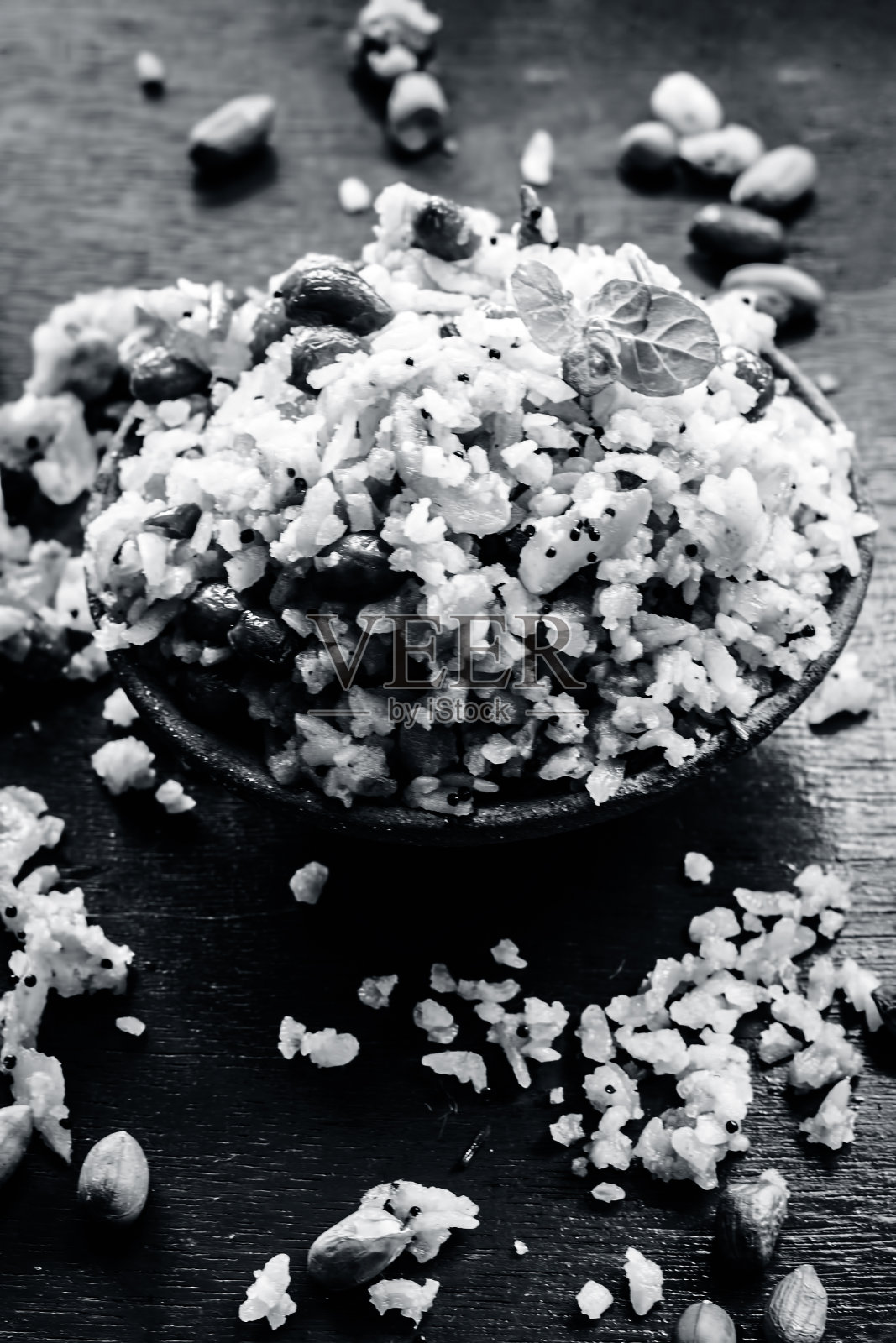 印度流行早午餐的近距离特写在一个粘土碗与干油炸花生在它是Poha batata或Pava batata在一个木制表面在深色哥特式颜色。照片摄影图片