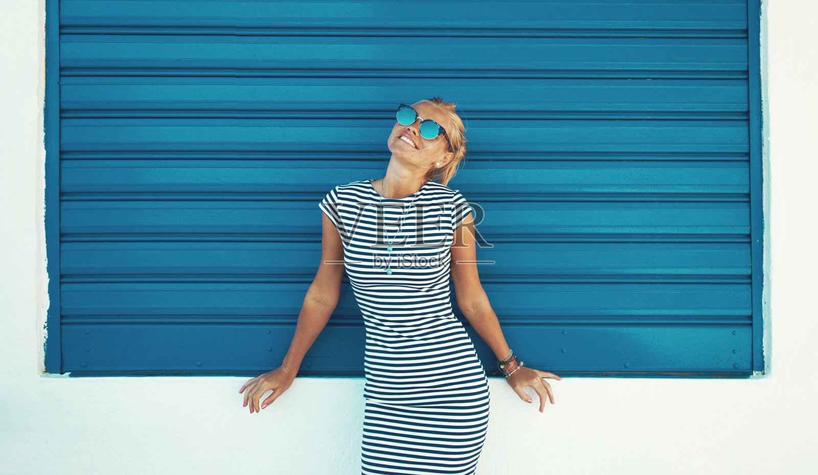 幸福年轻时尚的地中海女人在蓝色卷帘高时尚摆姿势照片摄影图片