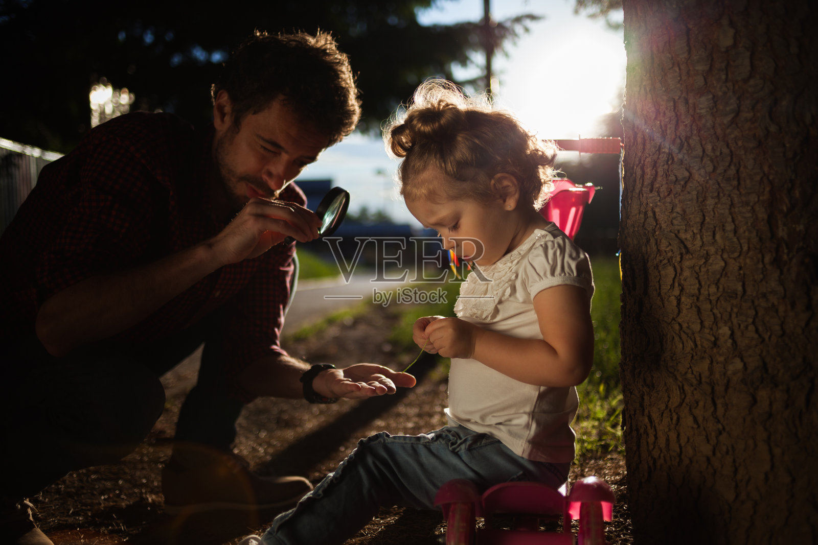 父亲拿着放大镜和婴儿在大自然中照片摄影图片
