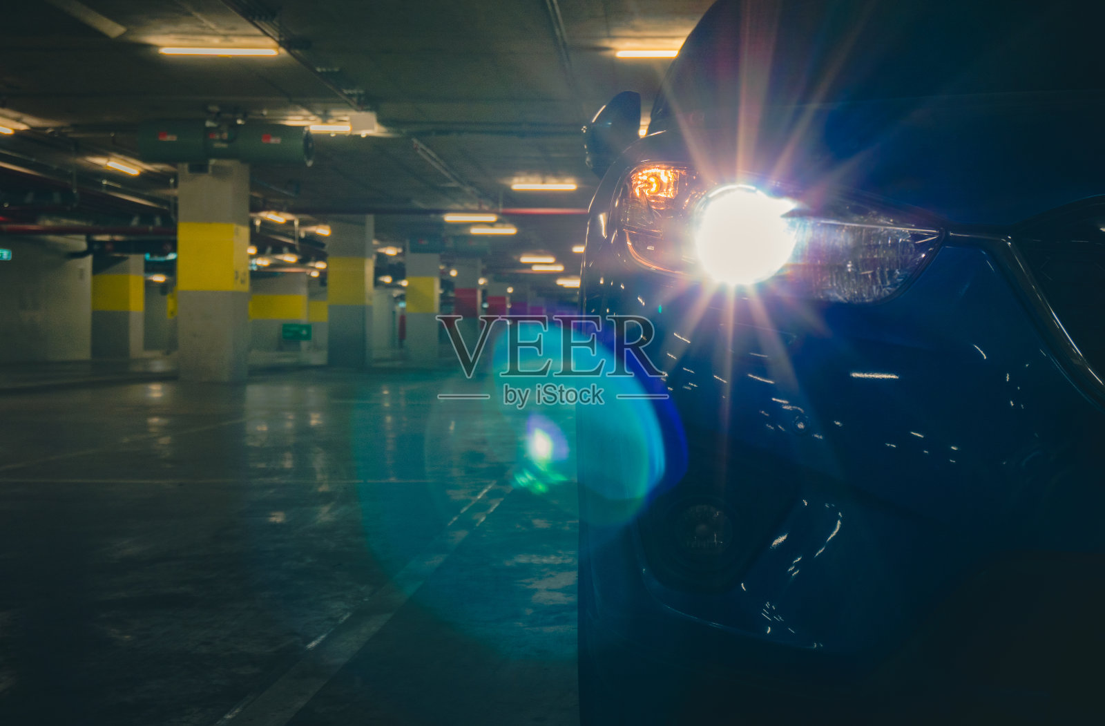 SUV车打开大灯灯,停在地下停车场购物。晚上的商场停车场。汽车孤独的停在夜晚。购物中心概念的偷车贼。照片摄影图片