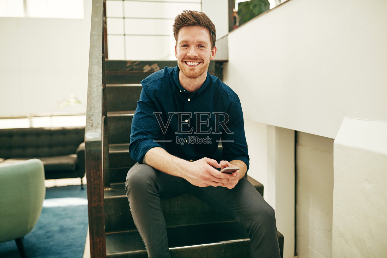 微笑的年轻商人在办公室的楼梯上阅读文本照片摄影图片