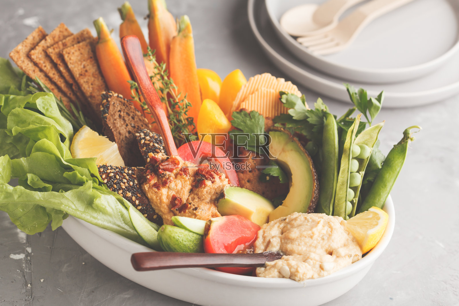 浅色背景上搭配蔬菜和各种小吃的素食阿拉伯蘸酱鹰嘴豆泥,健康纯素食品概念照片摄影图片