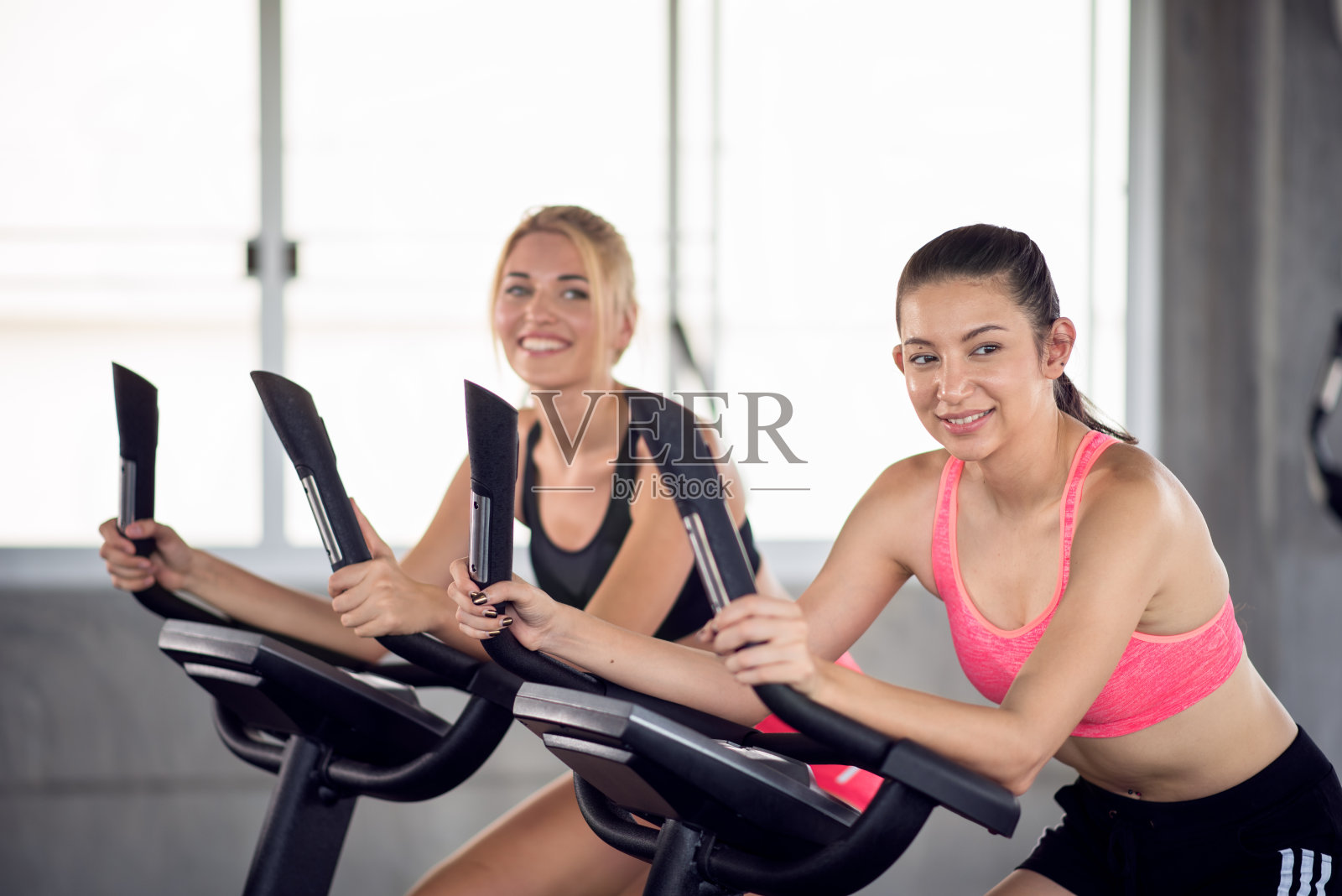 年轻女性在健身房的有氧器械上锻炼照片摄影图片