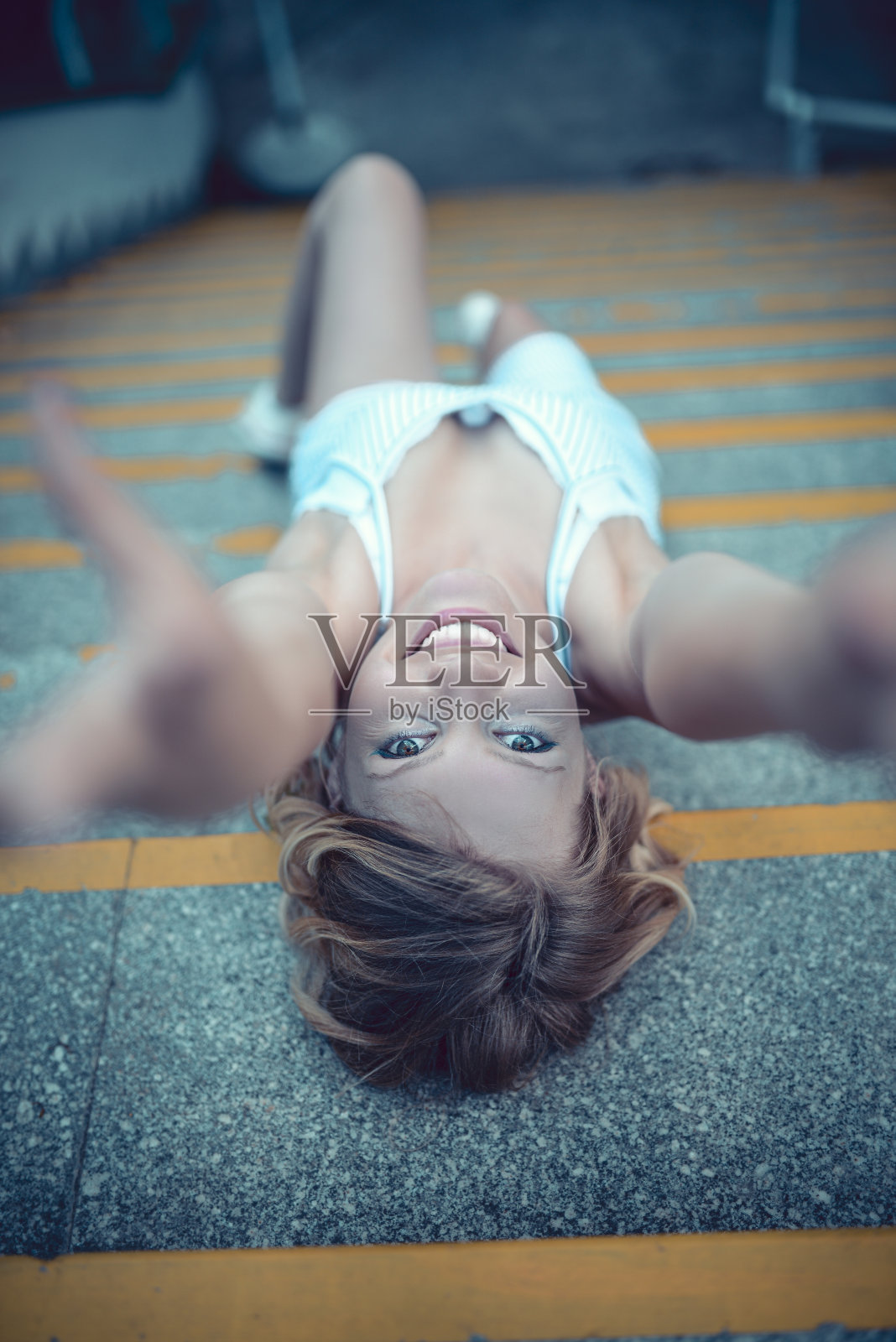 可爱的女性躺在台阶上,伸手拿相机照片摄影图片