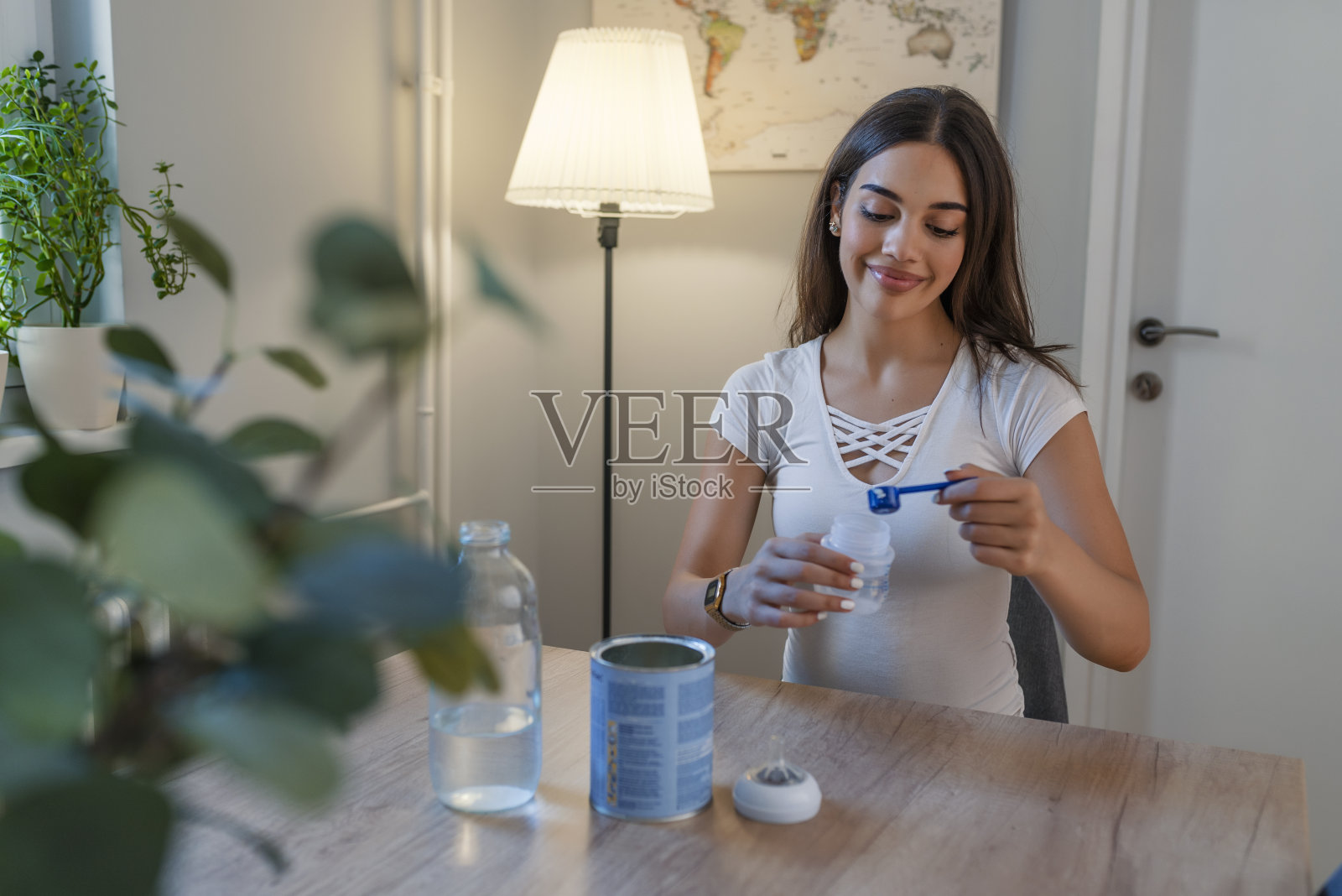 母亲正在用奶瓶制作婴儿配方奶粉,给刚出生的婴儿喂奶照片摄影图片