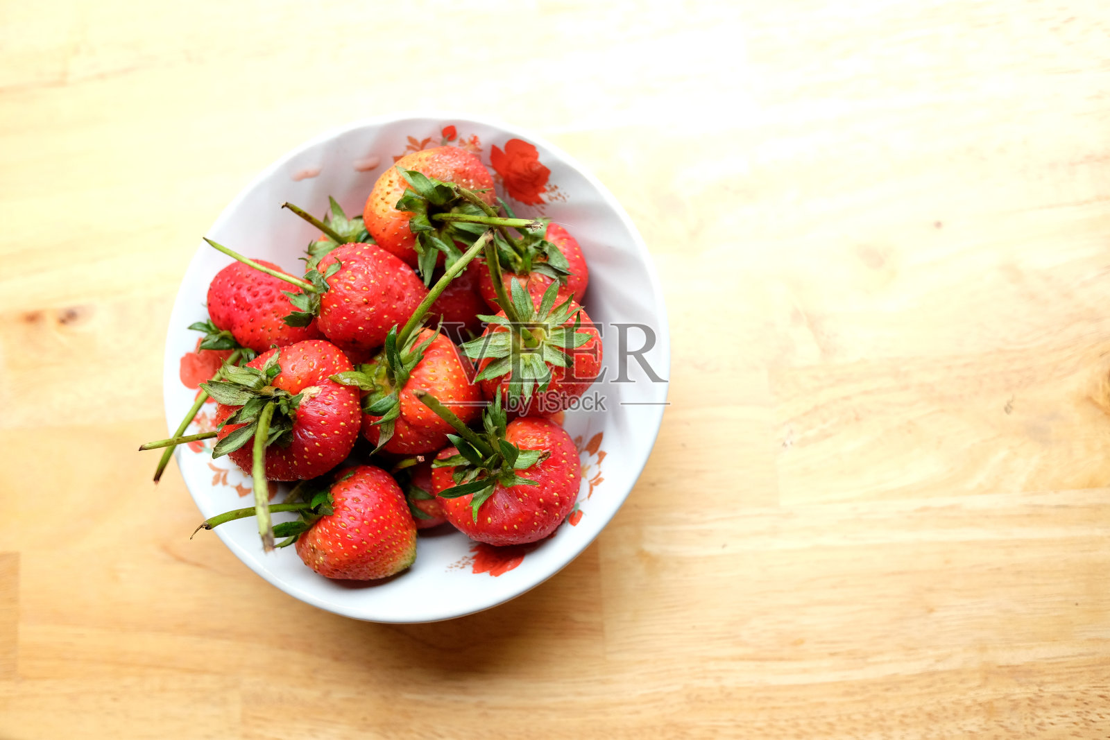 新鲜的草莓在白色的碗在自然的绿色背景木桌上。本空间照片摄影图片