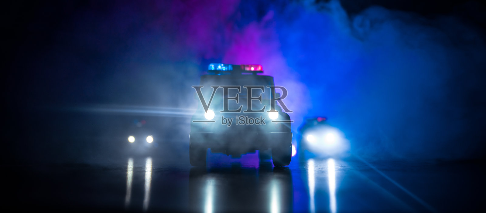 一辆警车在雾中追赶一辆汽车。911紧急反应警车超速驶往犯罪现场。有选择性的重点照片摄影图片