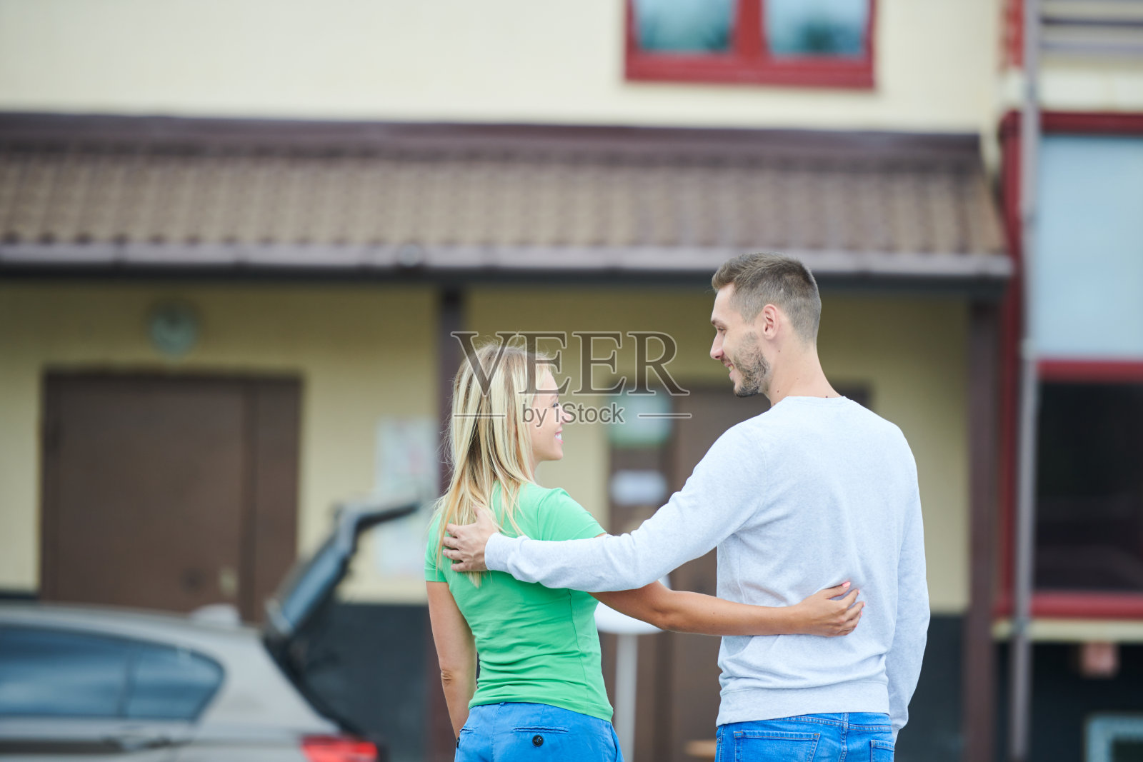 积极的年轻夫妇在休闲服装拥抱和看着对方,同时准备搬进新公寓,开始新生活的新房子概念照片摄影图片